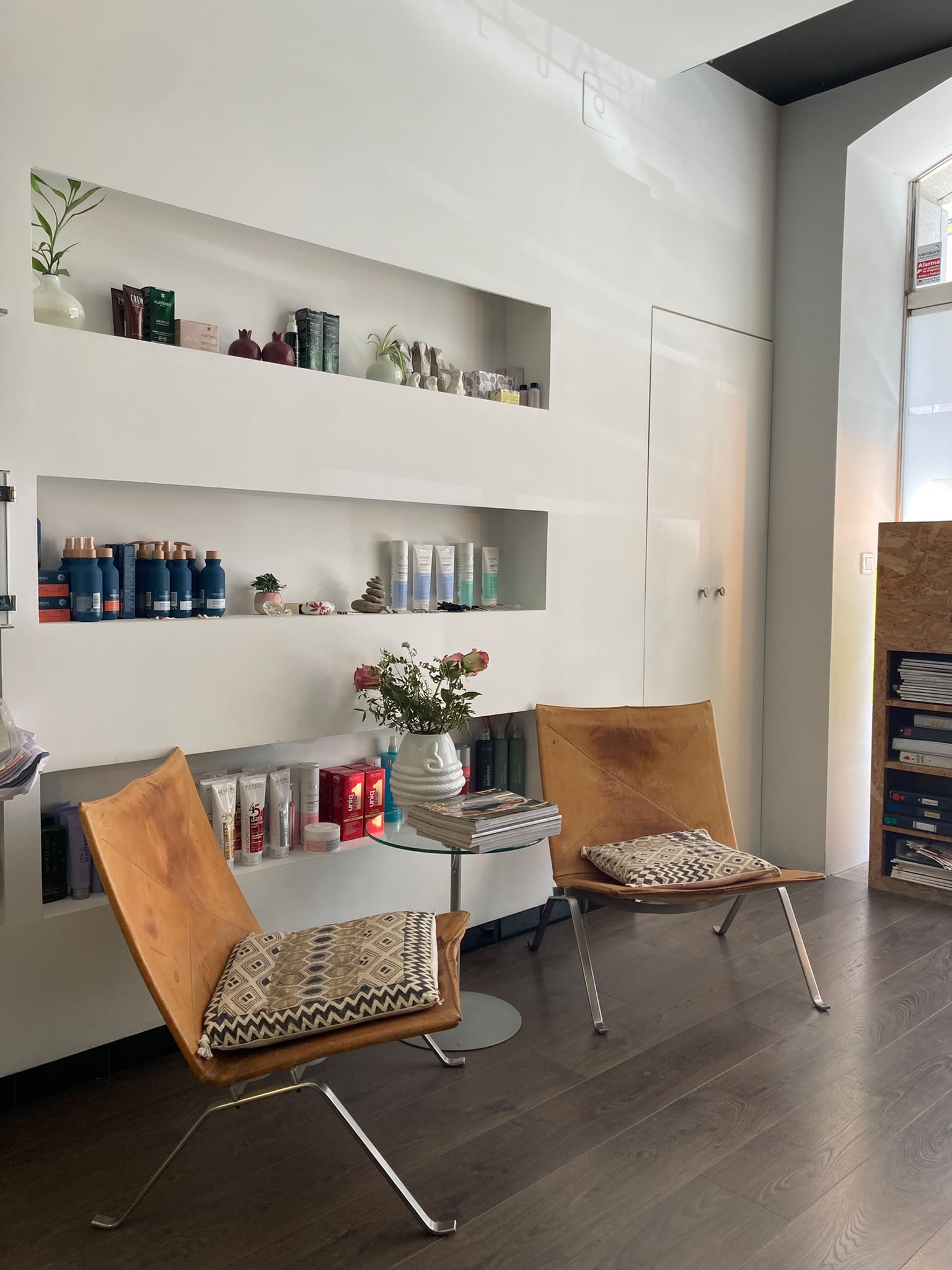 Rincón de espera con butacas de cuero y productos del salón